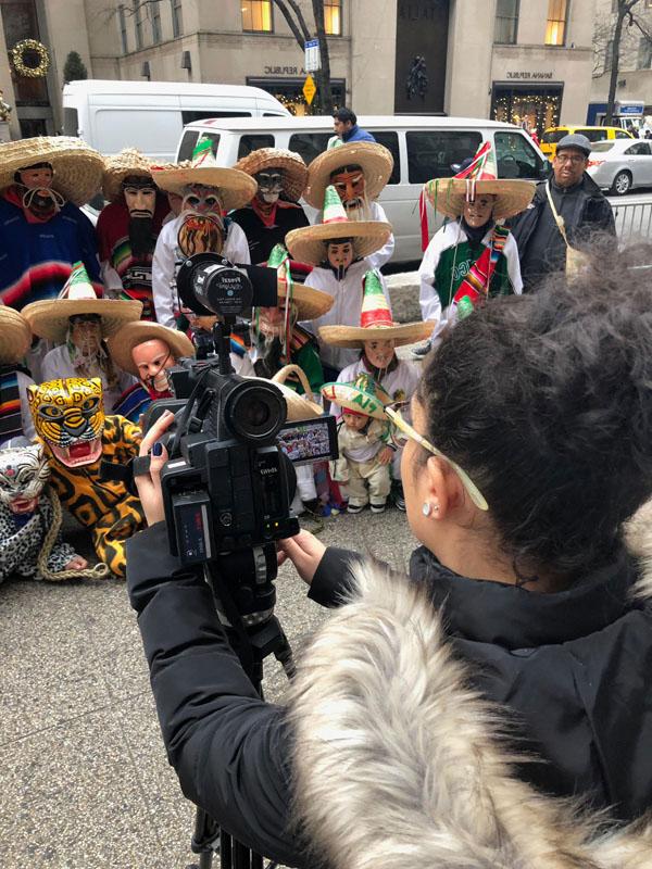 Franchesca on the street with a crowd, reporting the news